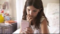 Young Girl In Bedroom Worried By Bullying Text Message