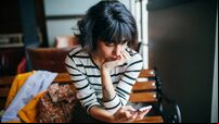 Happy woman using phone at cafe