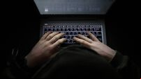 Person with a hoody typing at a computer in the dark. Suspicious online behavior