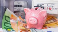 Piggy bank and Euro cash near an electricity meter and gas meter. Utility bills, consumption of electricity and gas for heating