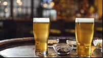 Glasses of Beer and Peanuts on a Wooden Table at a Pub, a Close Up