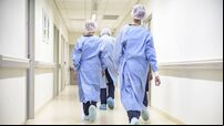 Team of medical staff in personal protective equipment walking in hospital corridor