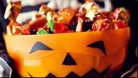 Boy in skeleton costume holding bowl full of candies