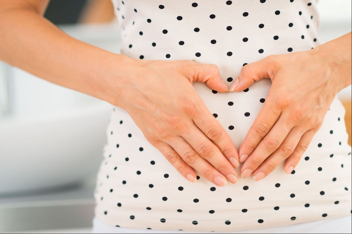 A generic photo of a woman creating a heart shape over her gut. A generic photo of a woman creating a heart shape over her gut.
