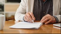 Hands of senior retirement woman writing a finance savings budget plan on paper or legal trust fund for after her funeral. Elder