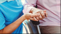 Nurse consoling a senior woman in the nursing home holding her hand in the nursing home