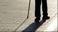 Silhouette of man walking with a cane, long shadow on pavement