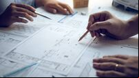 Engineering man showing blueprint detail for people buying house.