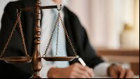 Closeup, scales and law on table, office and attorney man in blurred background with reading for crime analysis. Advocate, lawye