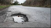 Deep road pothole filled with rainwater.
