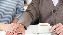 Close Up Of Woman Sharing Cup Of Tea With Elderly Parent