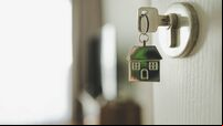 Open the door and door handle with a key and a keychain shaped house. Property investment and house mortgage financial real esta
