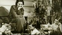 Mother watching three children playing by Christmas tree, (B&W)