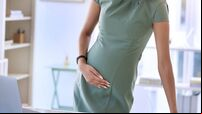 Shot of a young pregnant businesswoman standing alone in the office and suffering from abdominal pain